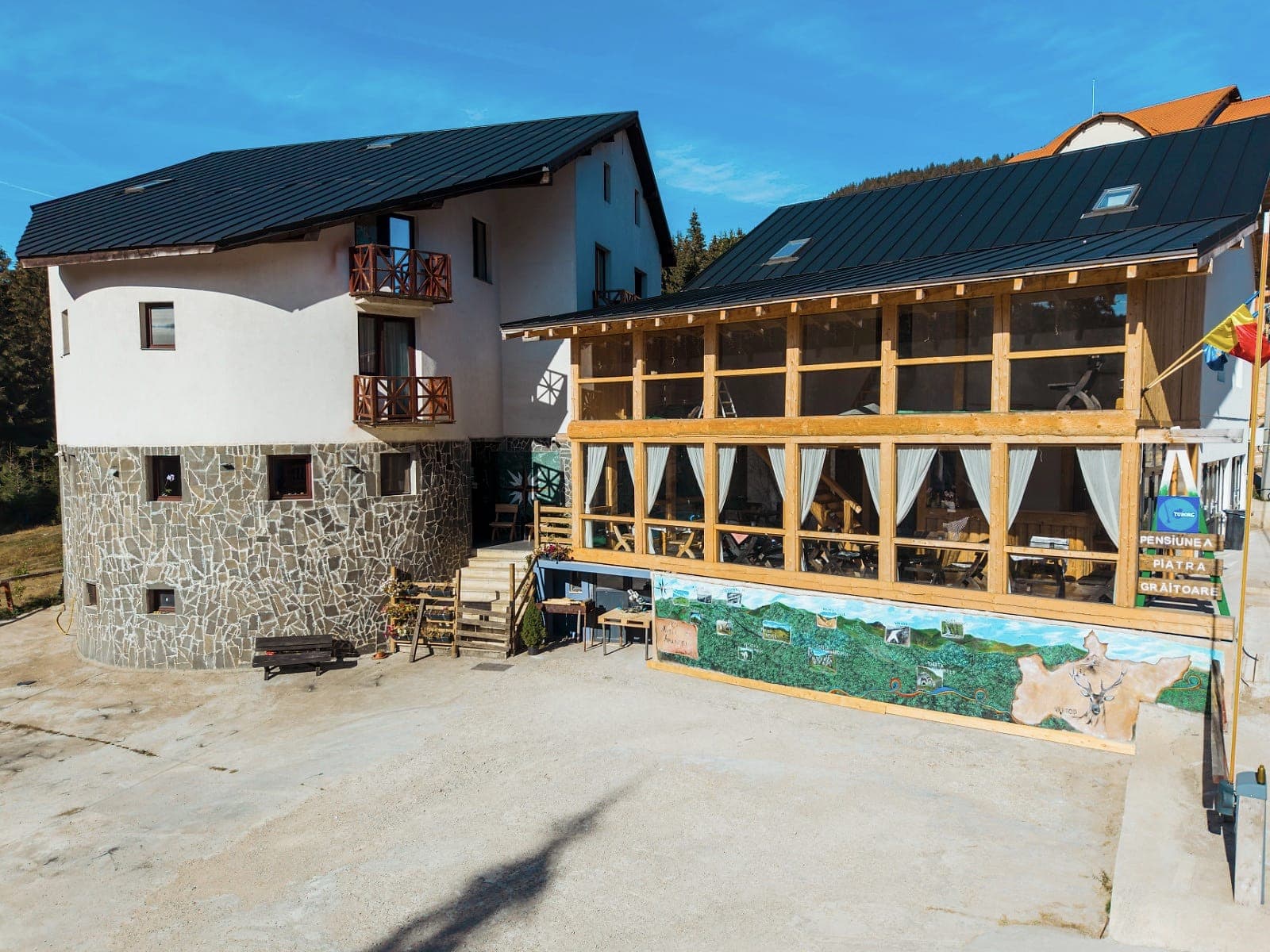 The front of the guesthouse: the round wall on its stone base, the wooden balconies and the wood-and-glass terrace